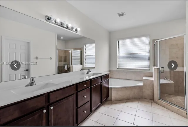 a spacious bathroom with a double vanity sink a large mirror and bathtub