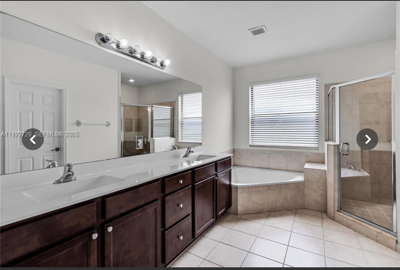 10091 West 35th Lane, Unit 10091 Hialeah, FL 33018 - Photo 19 of 32 a spacious bathroom with a double vanity sink a large mirror and bathtub