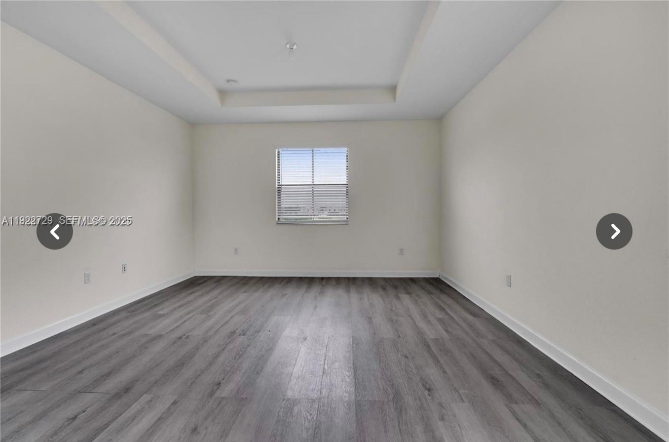 10091 West 35th Lane, Unit 10091 Hialeah, FL 33018 - Photo 25 of 32 an empty room with wooden floor and windows