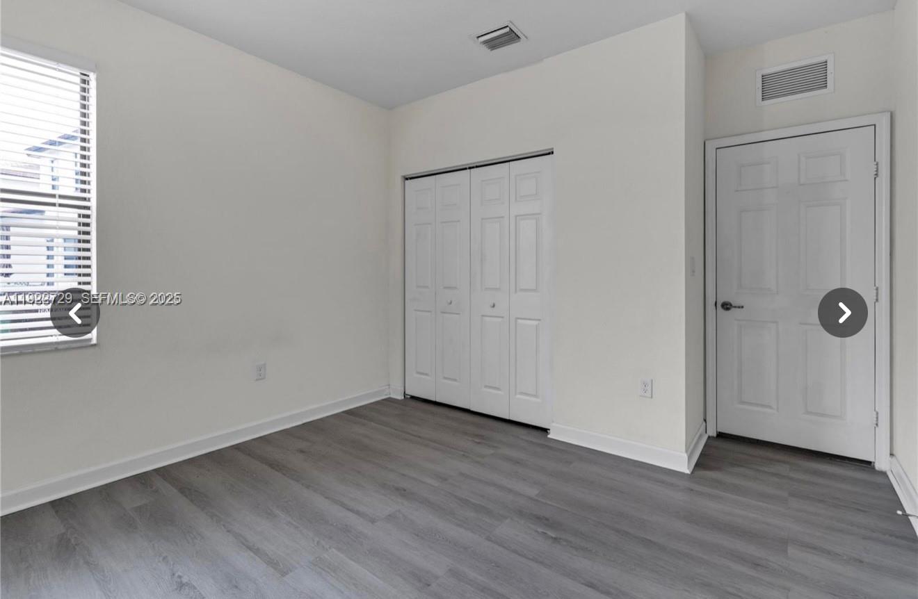 10091 West 35th Lane, Unit 10091 Hialeah, FL 33018 - Photo 26 of 32 a view of an empty room with wooden floor and a window