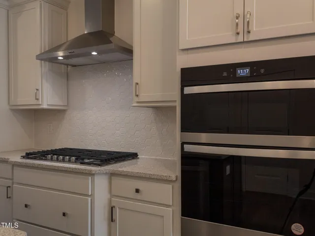 a kitchen with white cabinets and black appliances