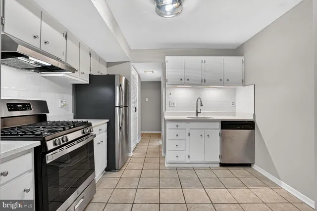 a kitchen with white cabinets a sink stove and refrigerator