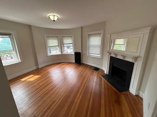 a view of a livingroom with wooden floor a fireplace and windows
