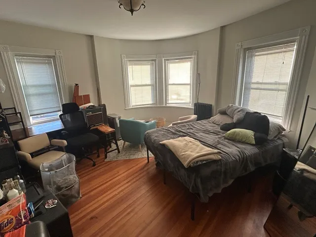 a spacious bedroom with a bed and wooden floor