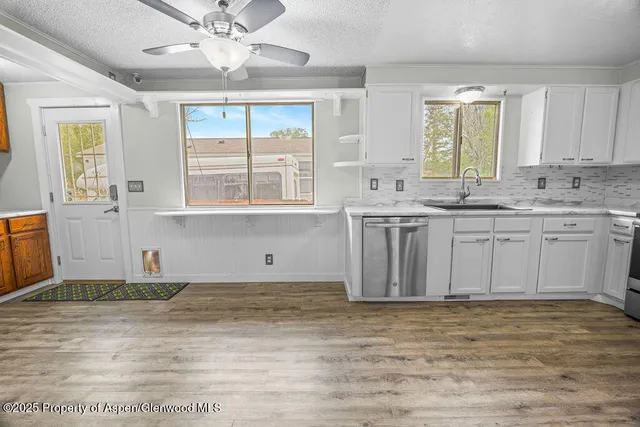 a kitchen with a sink a refrigerator a stove top oven and white cabinets