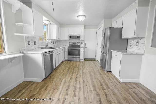 a view of a kitchen with an empty space and a refrigerator