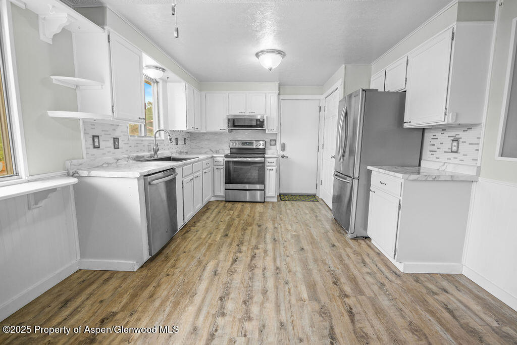 562 Rose Street Craig, CO 81625 - Photo 17 of 59 a kitchen with a sink a refrigerator a stove top oven and white cabinets