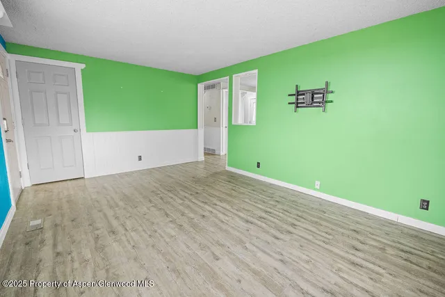 a view of an empty room with a window and wooden floor