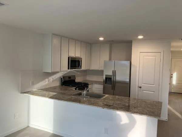 a kitchen with stainless steel appliances granite countertop a sink and a refrigerator