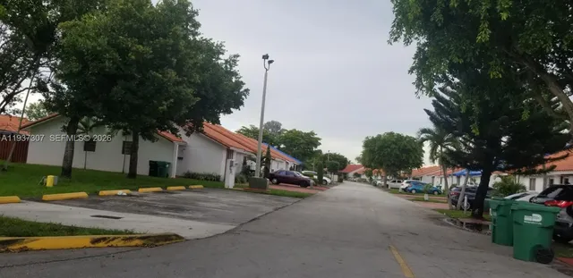a view of road with card parked on side and retail shops