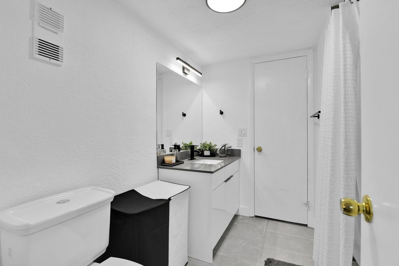 250 Northwest 67th Street, Unit 322 Boca Raton, FL 33487 - Photo 6 of 15 a bathroom with a granite countertop sink a toilet and shower