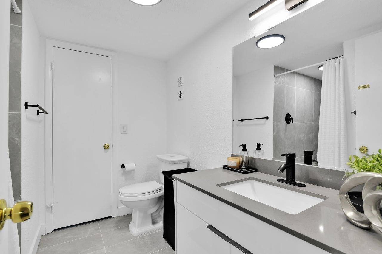 250 Northwest 67th Street, Unit 322 Boca Raton, FL 33487 - Photo 9 of 15 a en suite bathroom with a granite countertop sink a toilet and shower