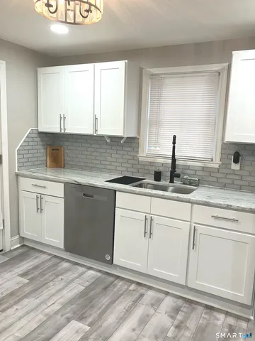 a kitchen with granite countertop white cabinets sink and white stainless steel appliances