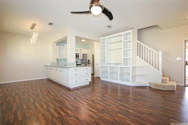 a view of an empty room with wooden floor and a ceiling fan