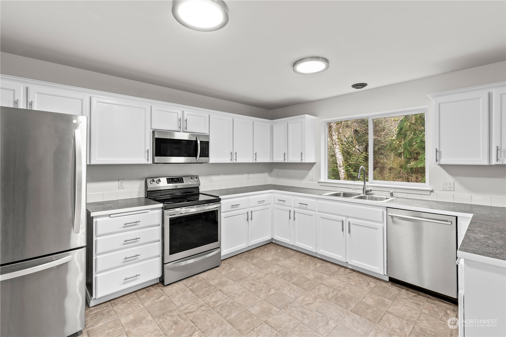 8226 Racca Court Southeast Olympia, WA 98513 - Photo 5 of 40 a kitchen with granite countertop a sink stainless steel appliances and window