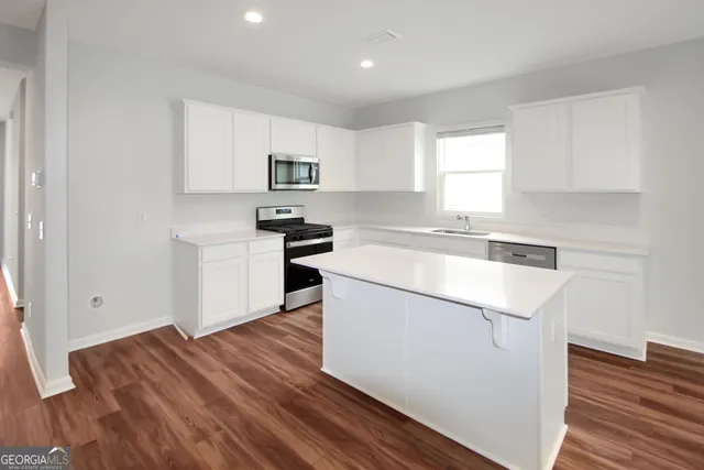 a kitchen with a refrigerator a sink and wooden floor