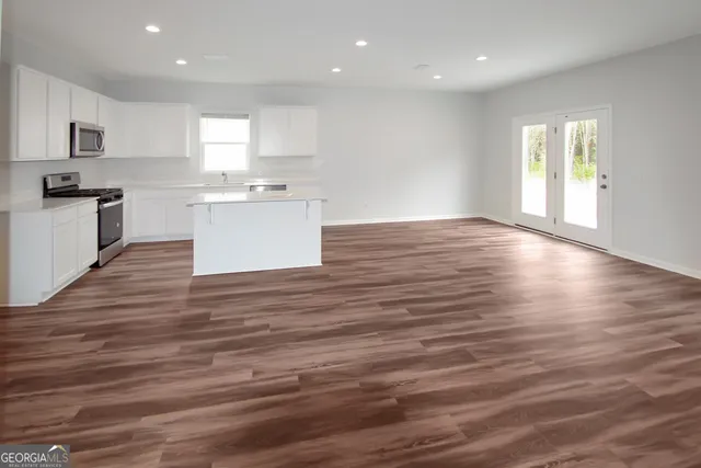 a large kitchen with stainless steel appliances granite countertop a large stove a sink dishwasher and a oven with white cabinets