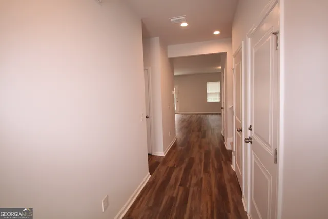 a view of a hallway with wooden floor and a bathroom