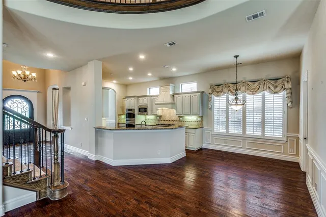 a living room with stainless steel appliances wooden floors and kitchen view