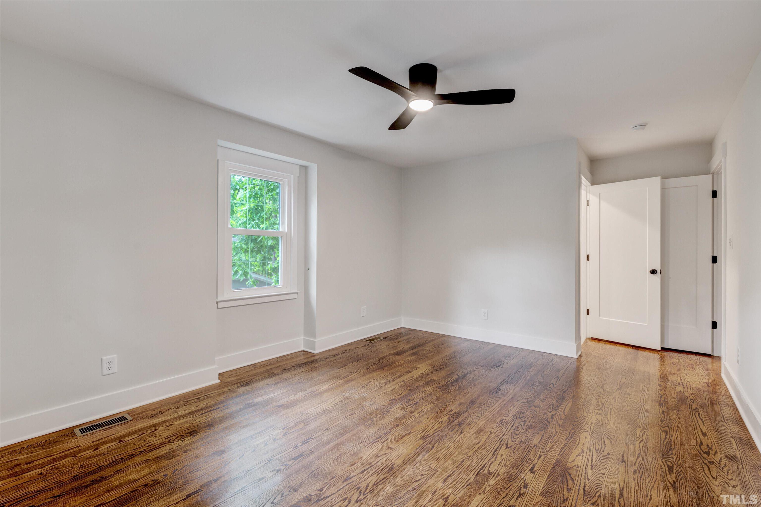 5400 Farley Drive Raleigh, NC 27609 - Photo 24 of 31 an empty room with wooden floor chandelier fan and windows