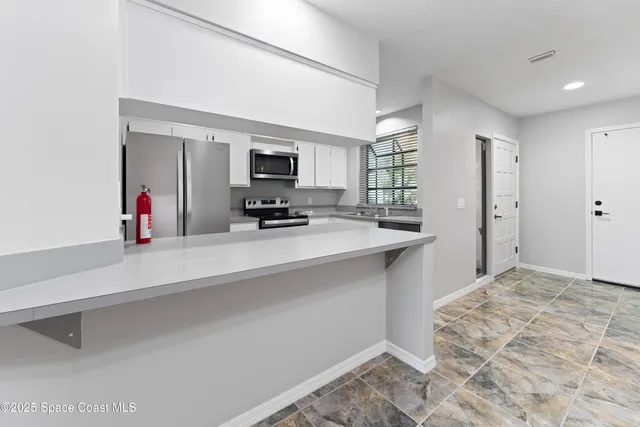a large white kitchen with sink refrigerator and microwave