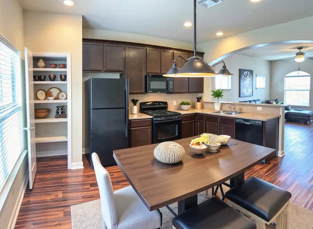 a kitchen with stainless steel appliances a dining table chairs and wooden floor