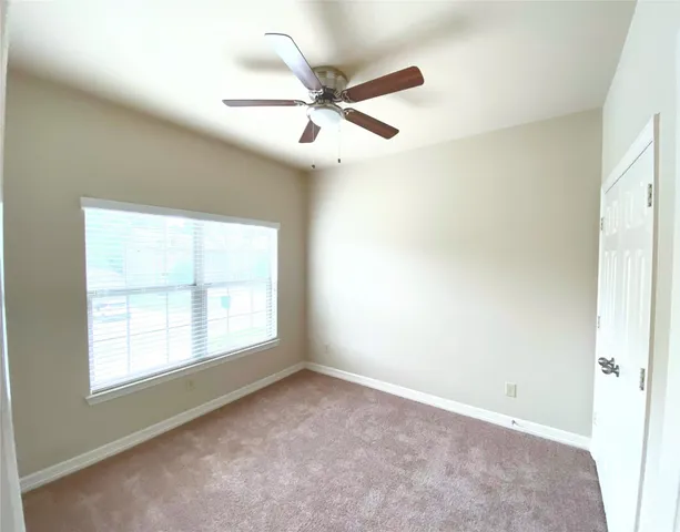 an empty room with a window and a fan