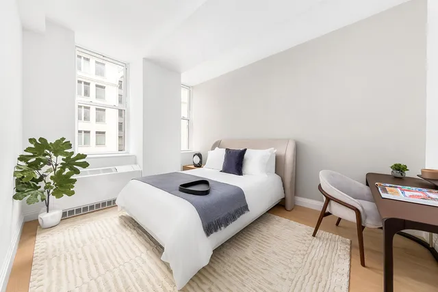 a bedroom with a bed table and a chair