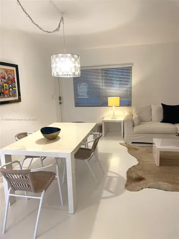 a living room with dining table couches a fireplace and a chandelier