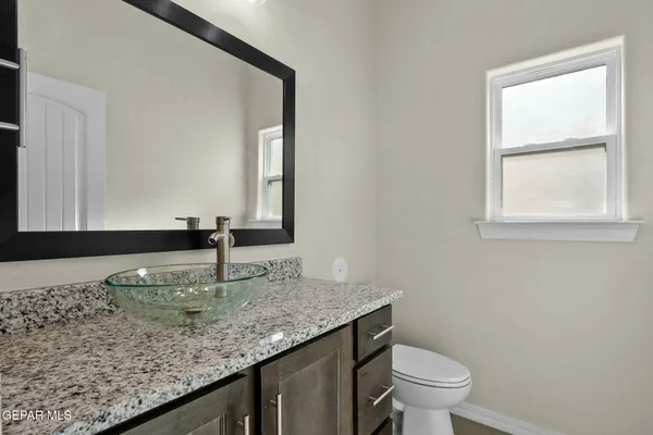 a bathroom with a granite countertop sink and a toilet