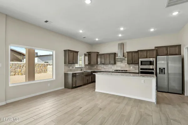a kitchen with stainless steel appliances granite countertop a refrigerator a sink dishwasher a oven with white cabinets and wooden floor