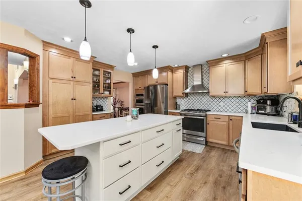 a kitchen with a stove a refrigerator and a dining table with wooden floor