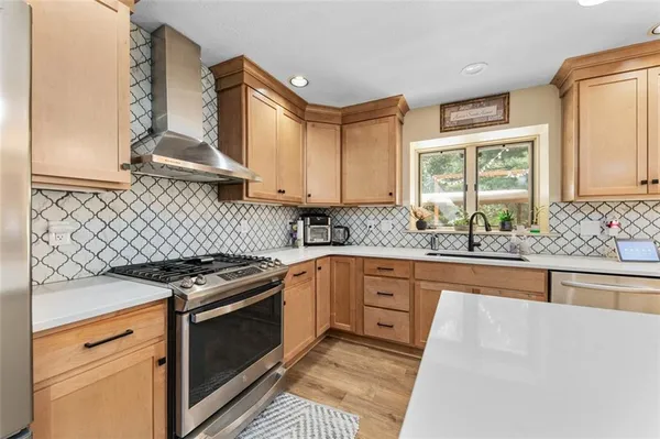 a kitchen with stainless steel appliances granite countertop a stove a sink and a microwave