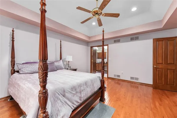a bedroom with a bed ceiling fan and a wooden floor