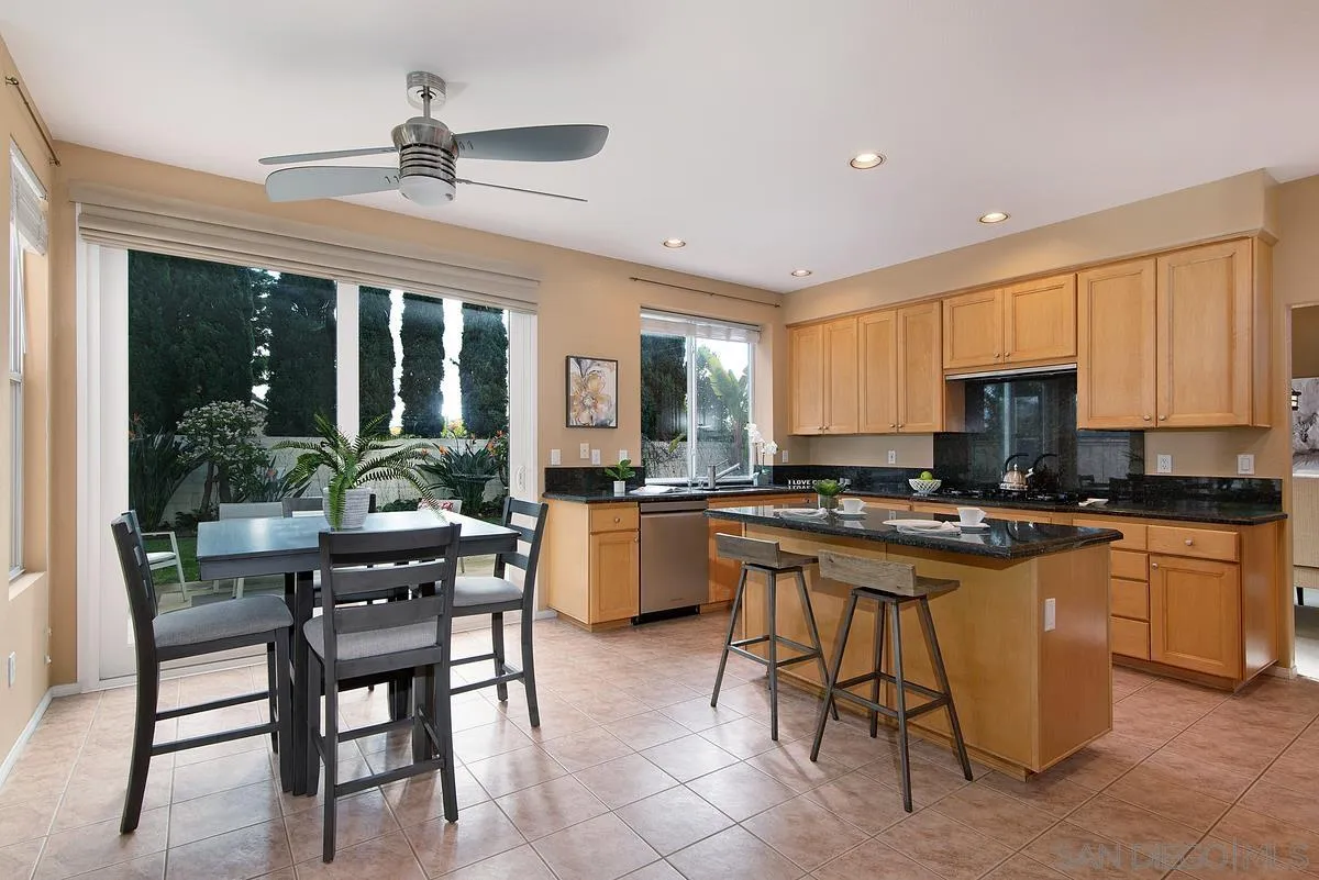 4951 Riding Ridge Road San Diego, CA 92130 - Photo 12 of 32 a kitchen with stainless steel appliances granite countertop table chairs sink and cabinets