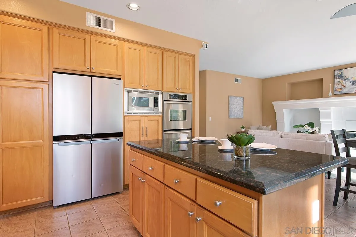 4951 Riding Ridge Road San Diego, CA 92130 - Photo 15 of 32 a kitchen with granite countertop a refrigerator a sink and cabinets