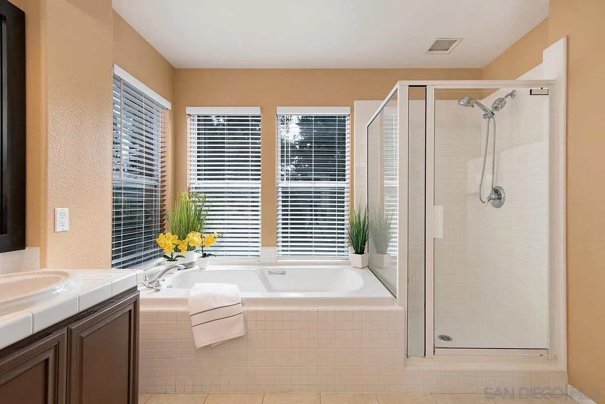 4951 Riding Ridge Road San Diego, CA 92130 - Photo 23 of 32 a bathroom with a granite countertop sink a bathtub and next to a window