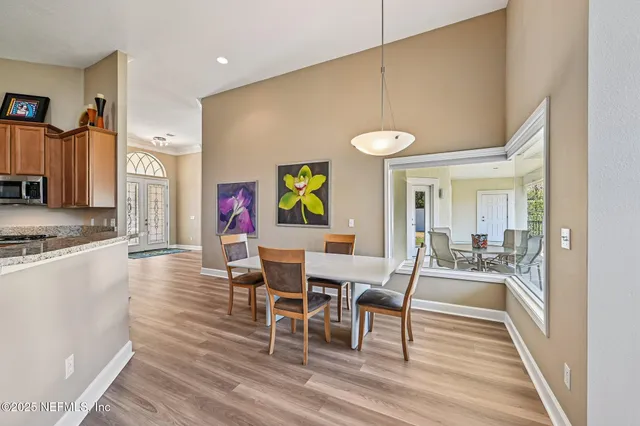 a view of a dining room with furniture one side kitchen view and wooden floor