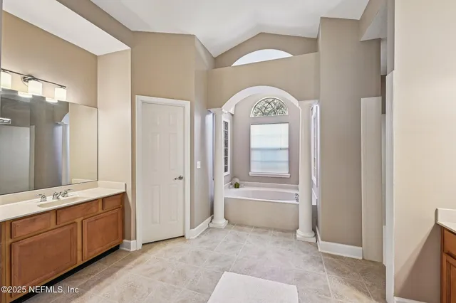a spacious bathroom with a tub sink and mirror