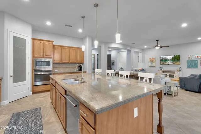 a kitchen with stainless steel appliances a dining table chairs refrigerator and microwave