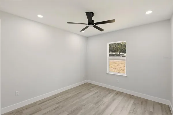 an empty room with a window and a ceiling fan