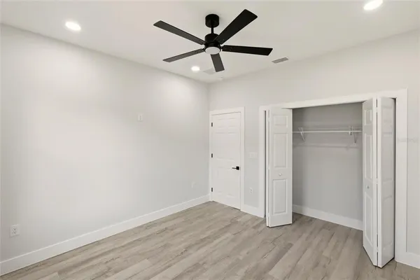 an empty room with wooden floor and ceiling fan