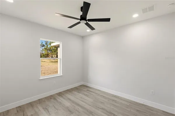 an empty room with a window and a ceiling fan