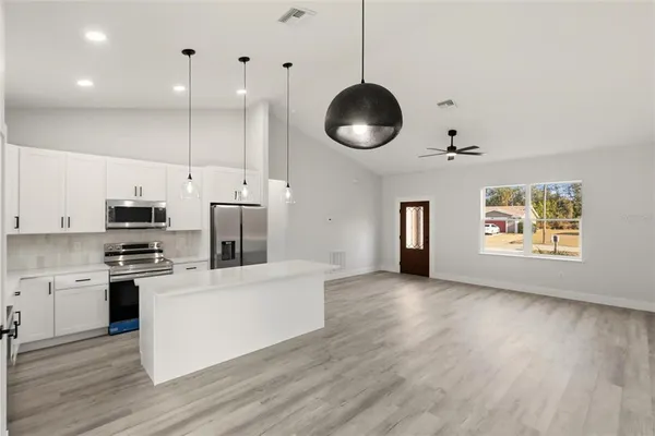 a kitchen with stainless steel appliances granite countertop a stove a sink dishwasher a refrigerator and a microwave with wooden floor