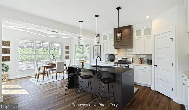a kitchen with stainless steel appliances granite countertop a stove a refrigerator a kitchen island a dining table and chairs with wooden floor