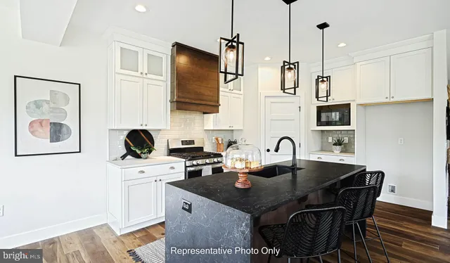 a kitchen with stainless steel appliances a stove a sink a microwave a refrigerator a dining table and chairs with wooden floor