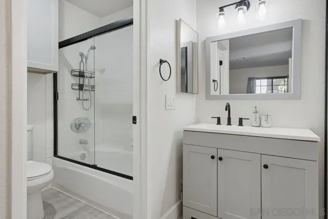 a bathroom with a granite countertop sink a toilet a mirror and shower