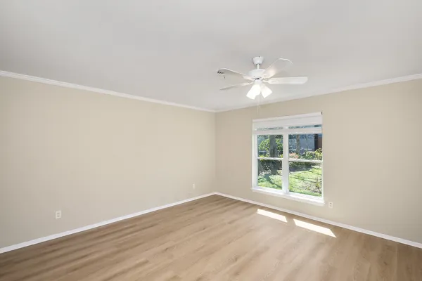 an empty room with windows and ceiling fan