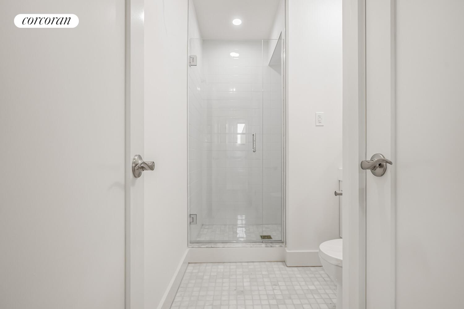 9511 Shore Road, Unit 609 Brooklyn, NY 11209 - Photo 12 of 16 a bathroom with a granite countertop shower and a toilet