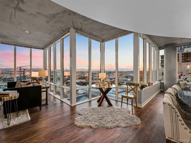 a living room with furniture large windows and wooden floor